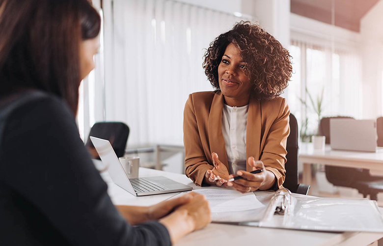 Photo of two women at a desk talking about insurance