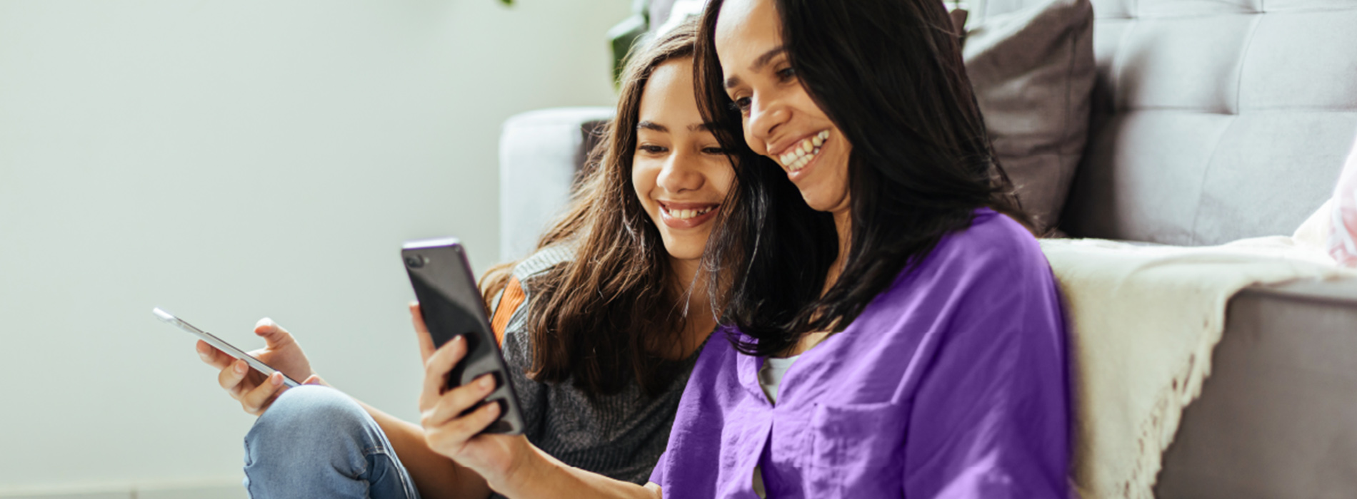 Image of mom and daughter looking at their phones by the couch