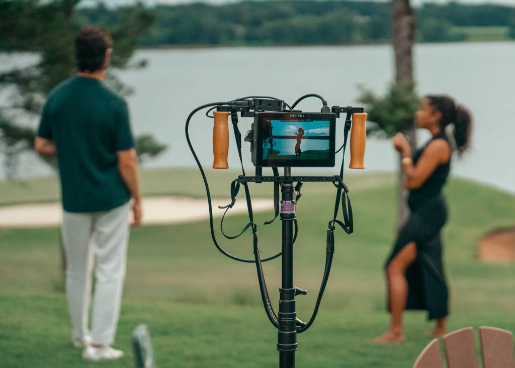 A camera viewfinder filming two models on a golf course